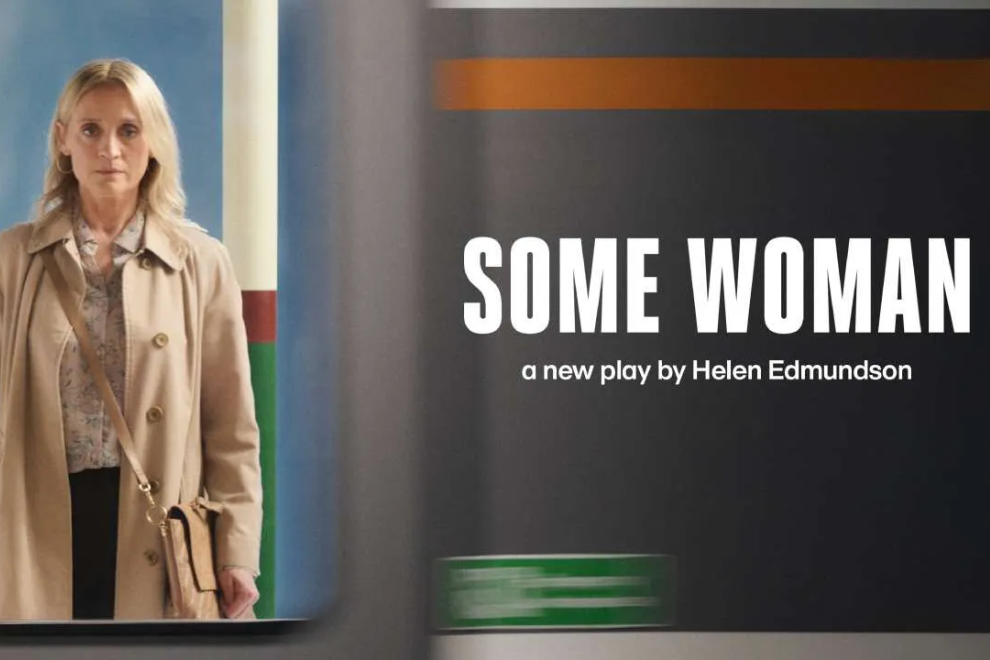 Woman in a beige coat stands beside a dark poster that reads 'SOME WOMAN,' a new play by Helen Edmundson.